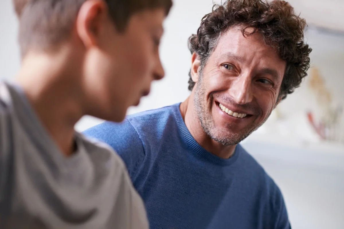 Smiling father looking at son during conversation - supportive parenting and positive family bond